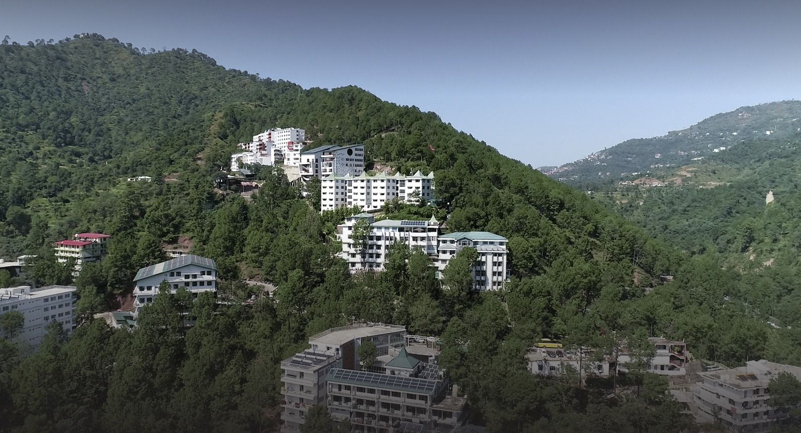 Aerial view of Shoolini University on a pine-covered hillside above Solan